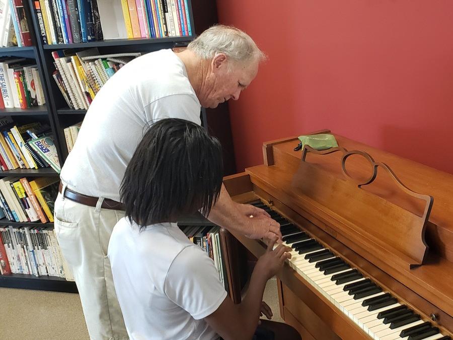 GYAC volunteer playing the piano with a student